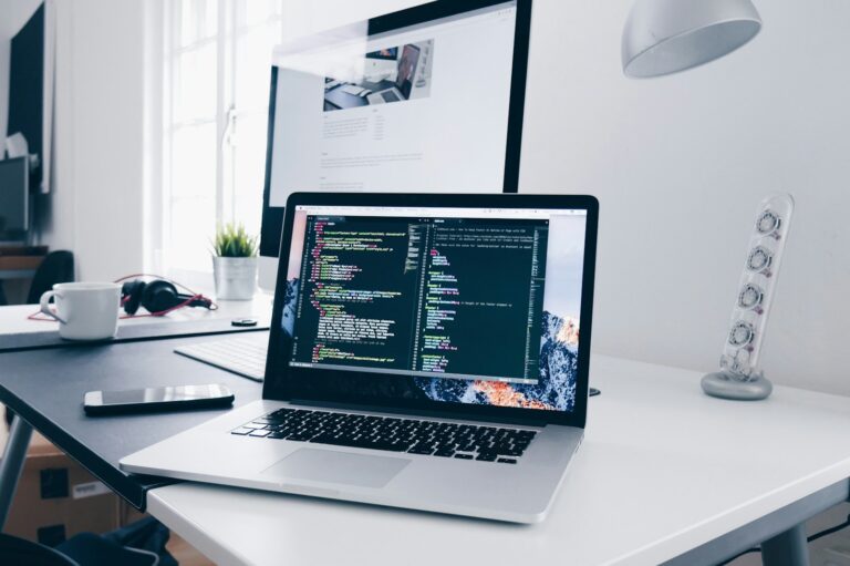 軟體開發介紹 A MacBook with lines of code on its screen on a busy desk