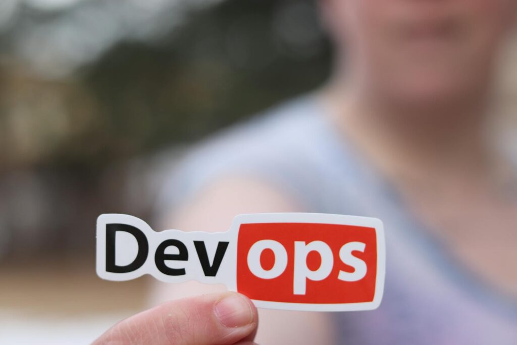 DevOps 介紹 A close-up image featuring a DevOps sticker held by a person outdoors.