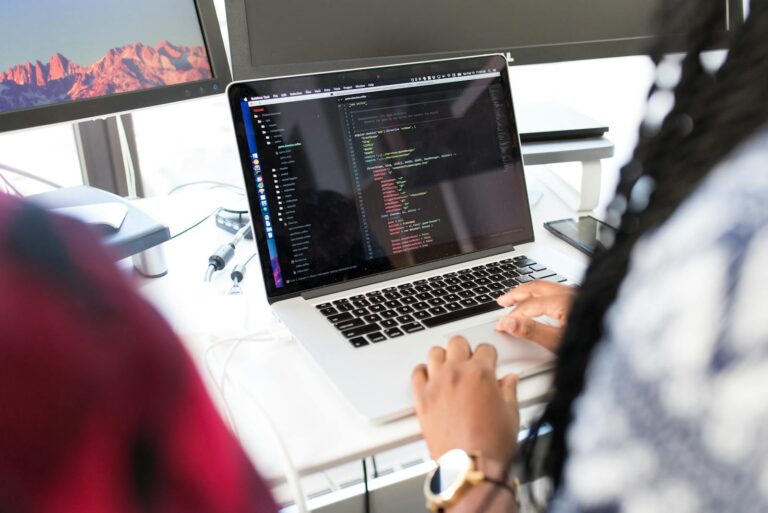 Lua 介紹 A woman coding on a laptop in a modern office environment with multiple monitors.
